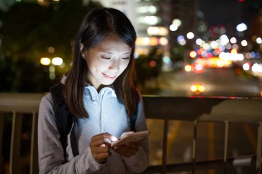 Geceleri cep telefonu kullanan bir kadın.