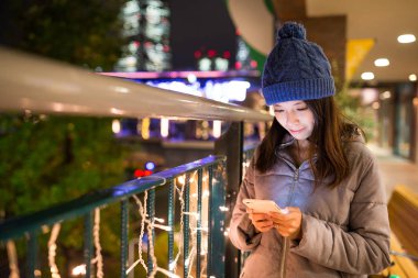 Geceleri cep telefonu kullanan bir kadın.