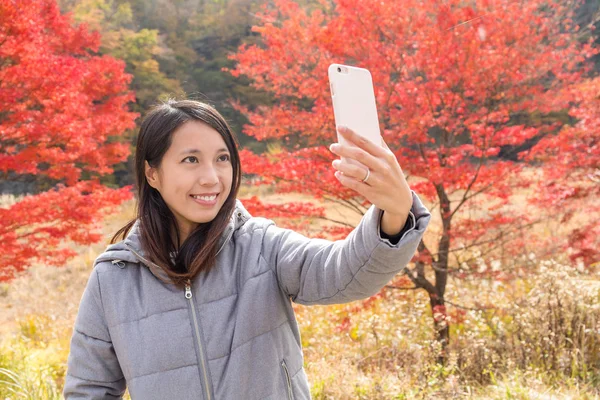 Женщина делает селфи по мобильному телефону в осенний сезон — стоковое фото