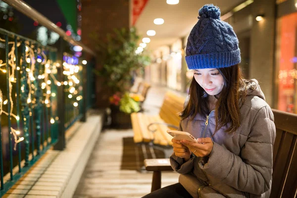 Geceleri cep telefonu kullanan bir kadın.