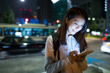 Geceleri cep telefonu kullanan bir kadın.