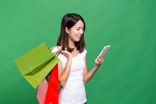 Donna che tiene borse della spesa e guarda il telefono cellulare — Foto Stock