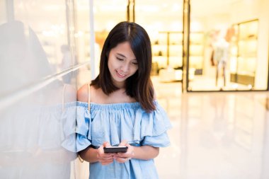 Alışveriş merkezinde cep telefonu kullanan kadın