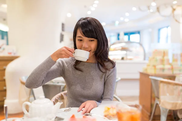 Женщина пьет кофе в магазине тортов — стоковое фото