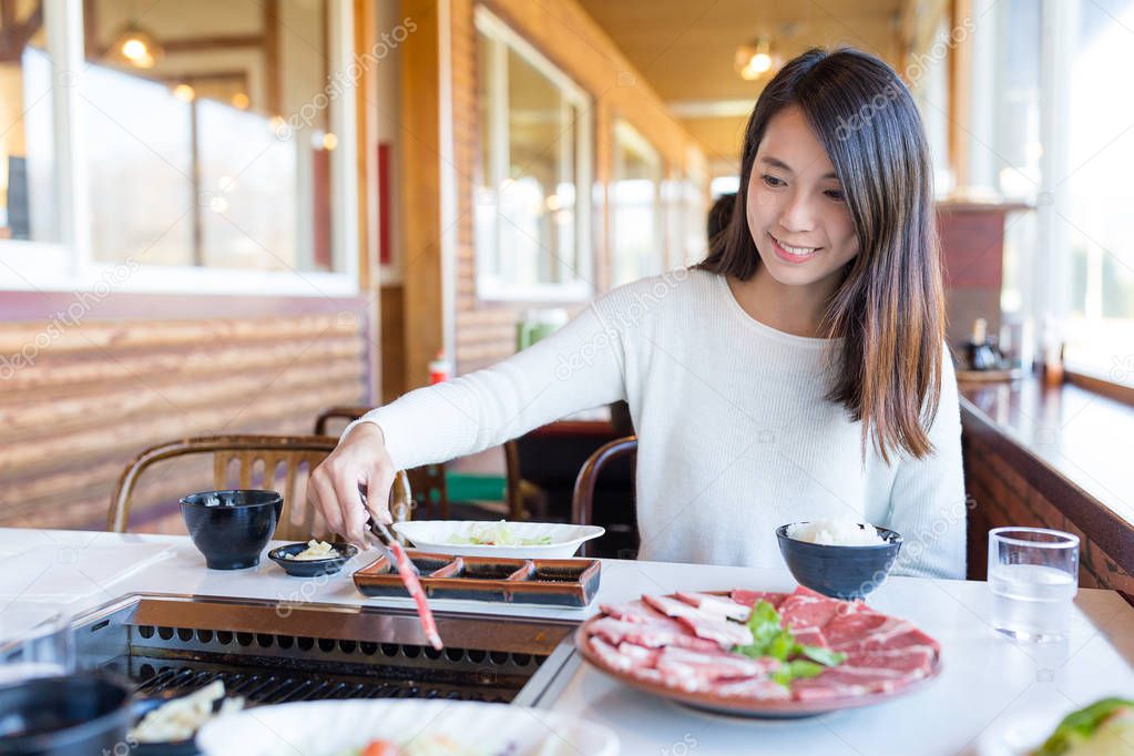 Woman having roasted sliced of beef in japanese yakiniku