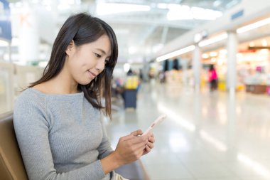 Gidiş salonunda cep telefonu kullanan kadın