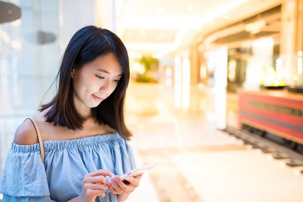 Vrouw met behulp van de mobiele telefoon bij winkelcentrum — Stockfoto