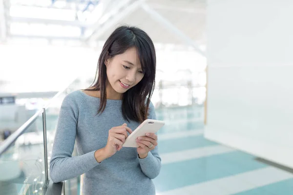 Vrouw met behulp van mobiele telefoon in de vertrekhal — Stockfoto