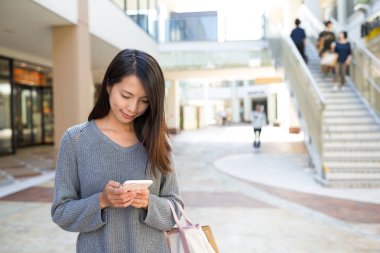 alışveriş merkezinde cep telefonu kullanan kadın