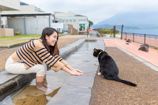 女性は通りの猫と遊ぶ — ストック写真