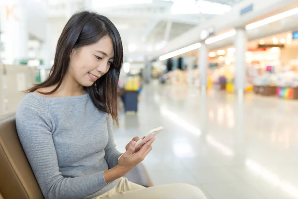Vrouw met behulp van mobiele telefoon op luchthaven — Stockfoto