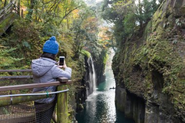 Cep telefonu alarak fotoğraf için Takachiho Gorge kullanan kadın 