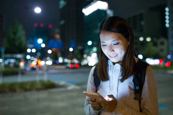 Vrouw met behulp van mobiele telefoon in de nacht in de stad — Stockfoto