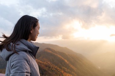 Dağ tepe günbatımında bakarak kadın