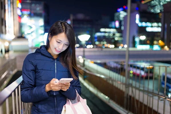 Женщина смотрит на мобильный телефон на открытом воздухе — стоковое фото