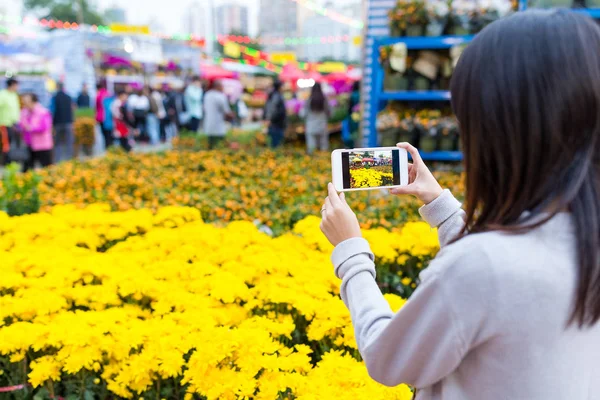 Frau fotografiert mit Handy auf Blumenmarkt — Stockfoto