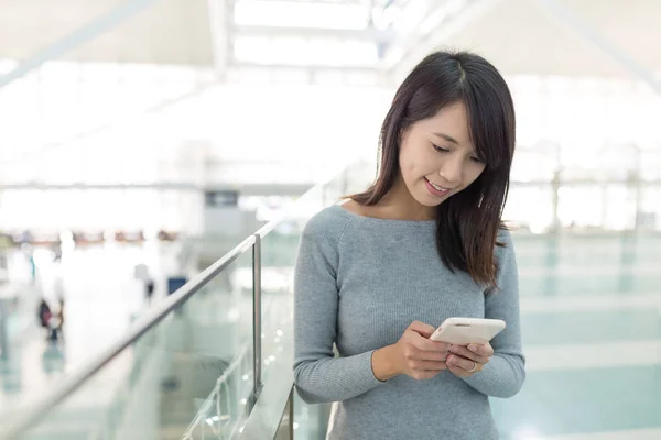 Vrouw leest op mobiel op luchthaven — Stockfoto