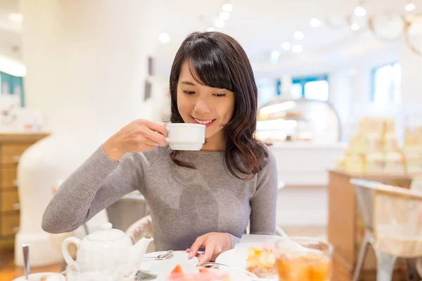 女性はケーキ屋さんで彼女のコーヒーを楽しむ — ストック写真