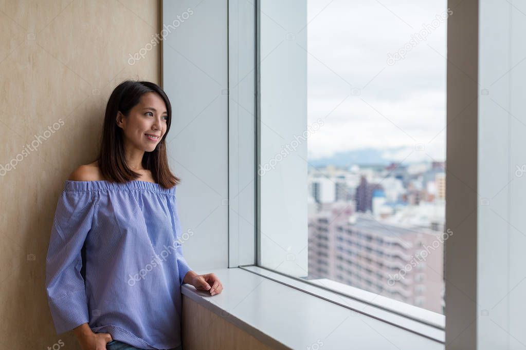 Woman looking out of window for cityscape