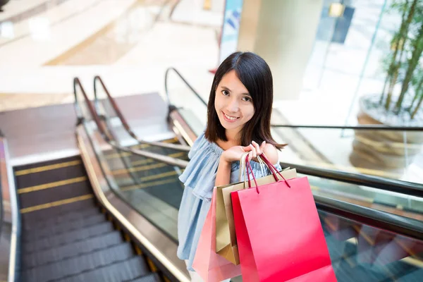 Frau hält Einkaufstüten auf Rolltreppe — Stockfoto