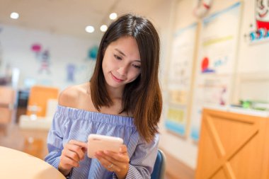 Kitaplıkta cep telefonu kullanan kadın