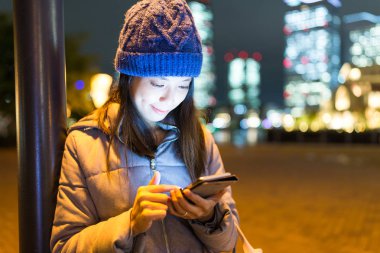 Geceleri cep telefonu kullanan bir kadın.