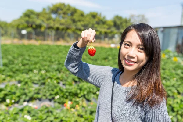 Jonge vrouw met aardbeien in de tuin — Stockfoto