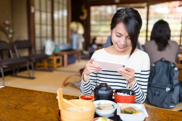 Женщина фотографируется с сотовым телефоном во время еды — стоковое фото