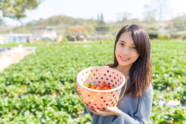 Junge Frau hält einen Korb mit Erdbeeren — Stockfoto