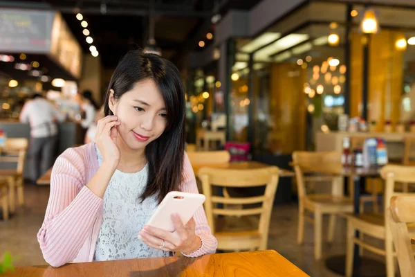 Женщина, использующая мобильный телефон в магазине тортов — стоковое фото