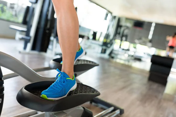 Donna che si allena su un allenatore ellittico in palestra — Foto Stock