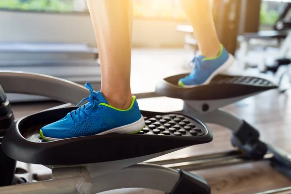 Mujer está entrenando en máquina elíptica —  Fotos de Stock