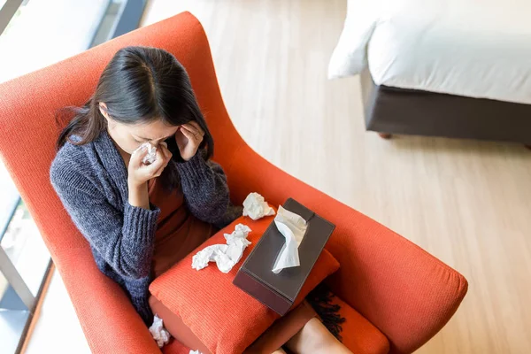 Vrouw niezen en zittend op de Bank thuis — Stockfoto