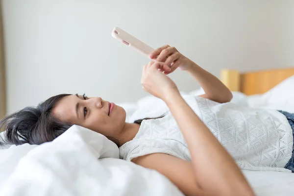 Frau benutzte Handy auf Bett — Stockfoto