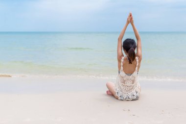 Plajda yoga yapan bir kadın.