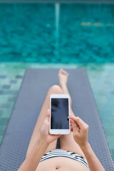 Woman using mobile phone with swimming pool