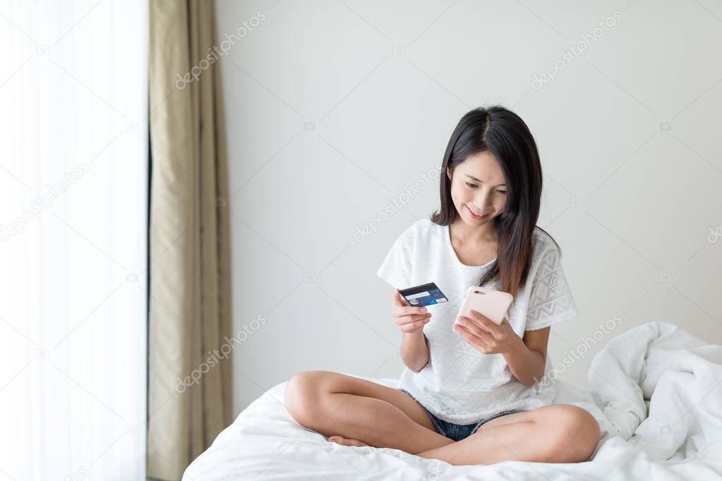 Woman using mobile phone and credit card to shopping online