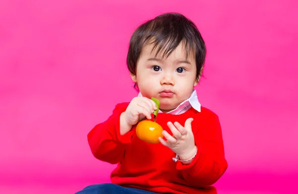 Азиатский мальчик держит мандарин — стоковое фото