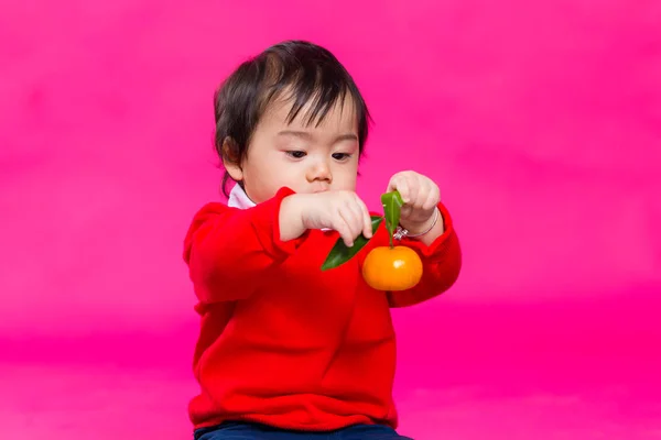 Söt kinesiska baby håller en tangerine — Stockfoto