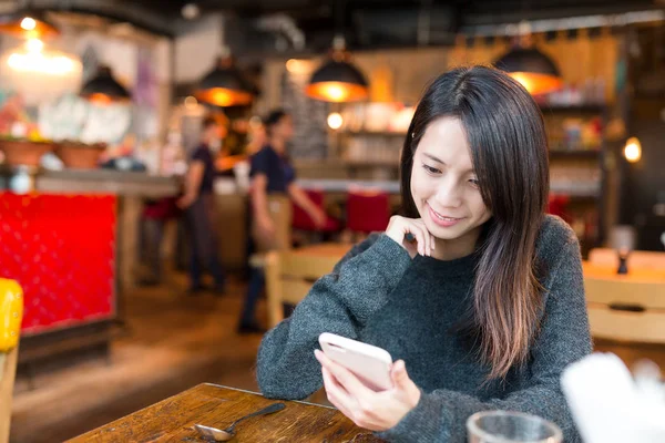 Kobieta, patrząc na telefon komórkowy w kawiarni — Zdjęcie stockowe