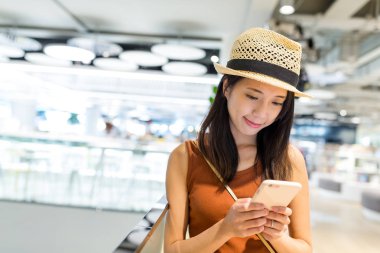 Alışveriş merkezinde cep telefonu kullanan kadın