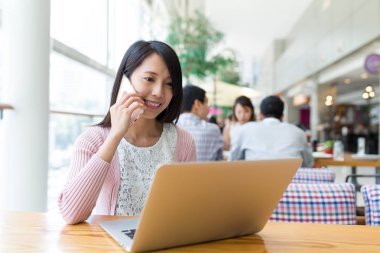Cep telefonundan arama ve bilgisayarı kullanan kadın