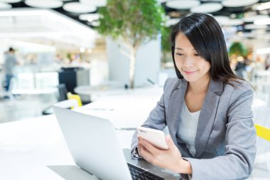 Cep telefonundan kontrol ve dizüstü bilgisayar kullanan iş kadını