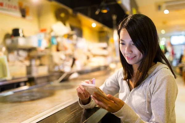 Женщина, использующая мобильный телефон в ресторане Окономияки — стоковое фото