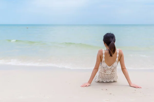 Kobieta się opalać i siedzi na plaży — Zdjęcie stockowe