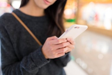 Kadın manifatura bir şey üstünde smartphone