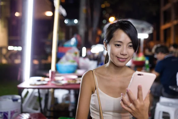 Woman using mobile phone in night market