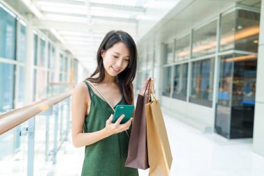Alışveriş torbaları tutarak ve cep telefonuyla kadın