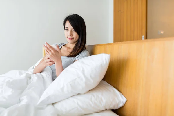 Mulher usando telefone celular na cama — Fotografia de Stock