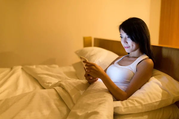 Frau arbeitet nachts mit Handy im Bett — Stockfoto